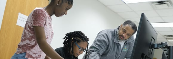 Students looking over a monitor